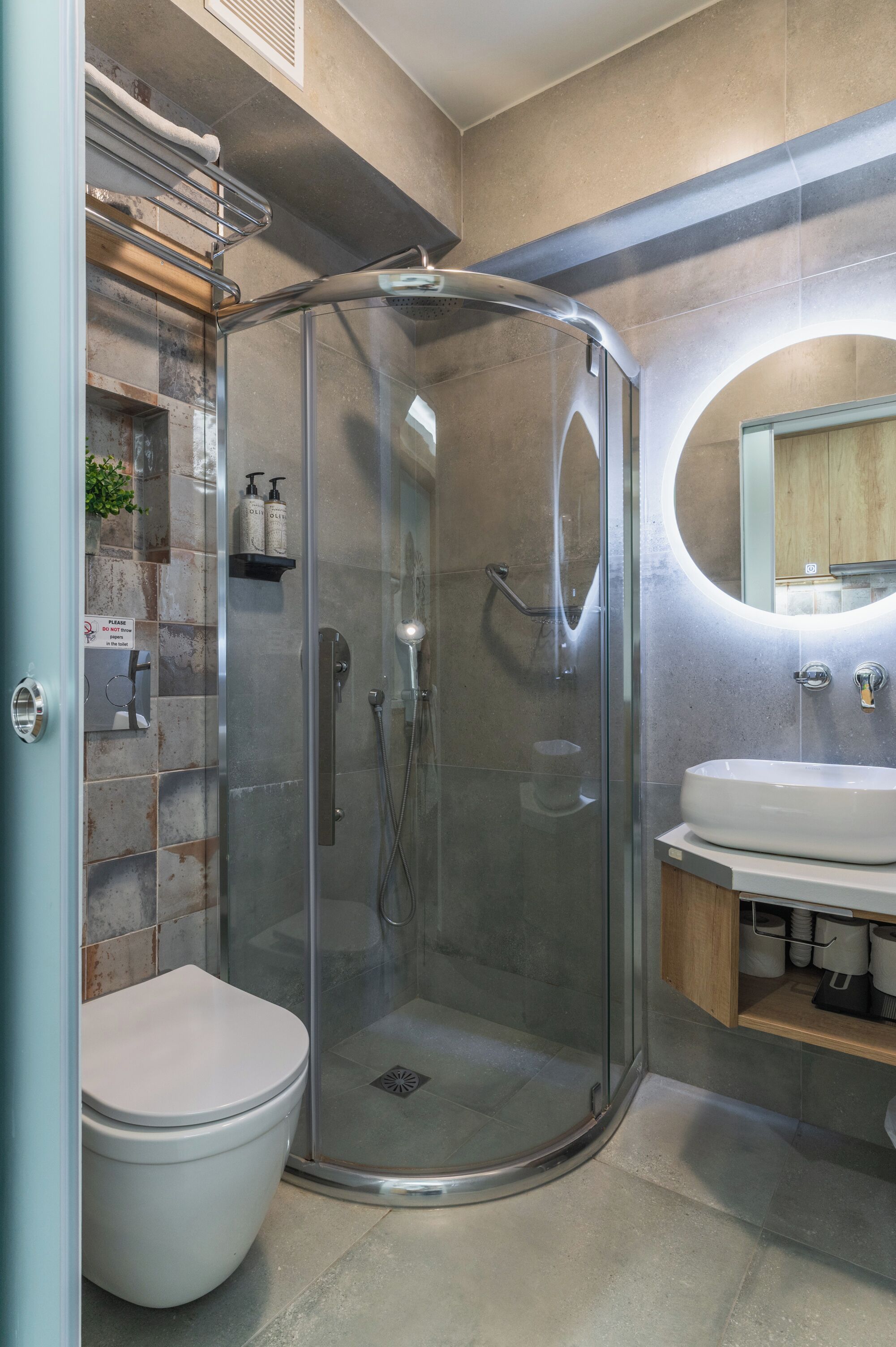 Une salle de bain moderne avec une douche à parois de verre, des toilettes blanches et un lavabo avec un miroir au-dessus.