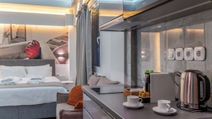 Ett modernt hotellrum med en säng, en soffa, en kaffebryggare och en vattenkokare.