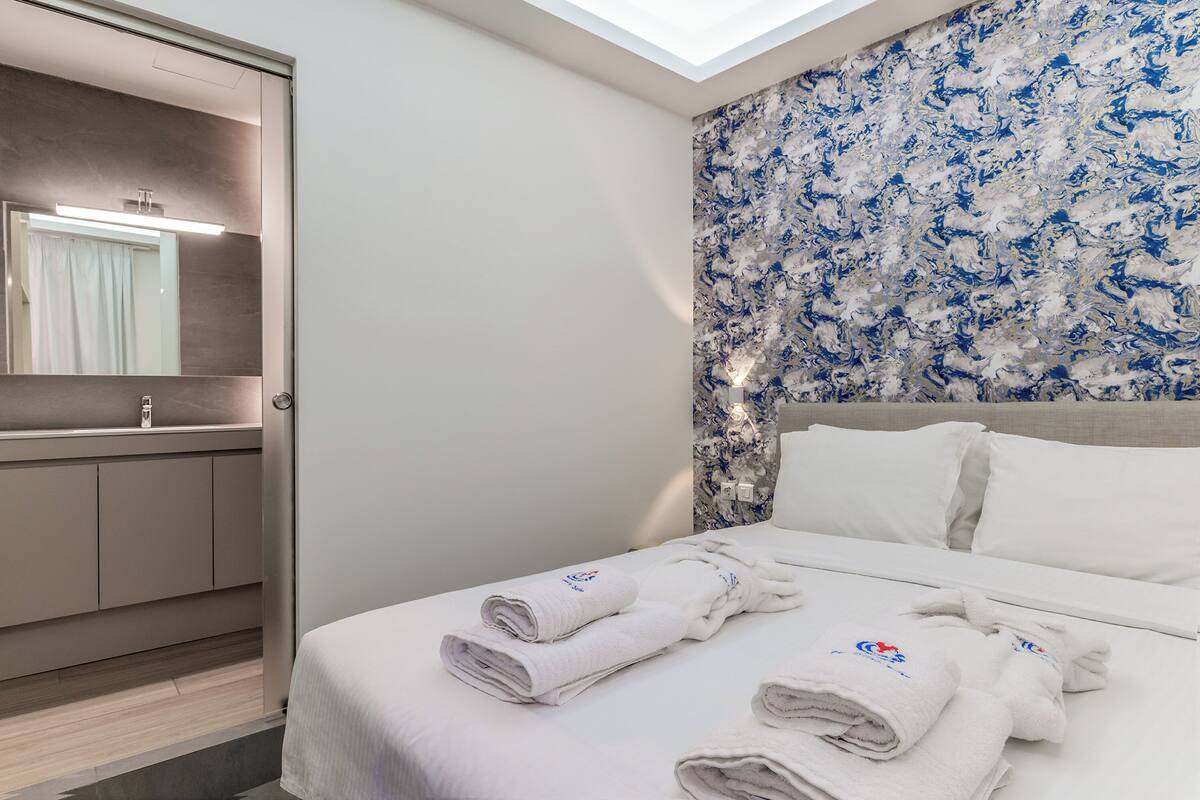 A hotel room with a bed, a bathroom, and a large window.