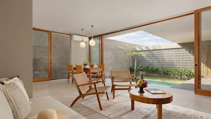 Un interior moderno con sofá, sillas, una mesa de comedor y vista a una piscina.