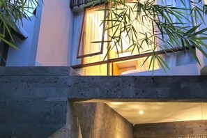 A building exterior with a window, a concrete structure, and a plant. - Pulang Villas Pererenan (Bali)