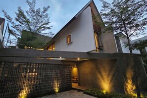 Una casa moderna con techo inclinado, una chimenea visible y una entrada protegida con valla.
