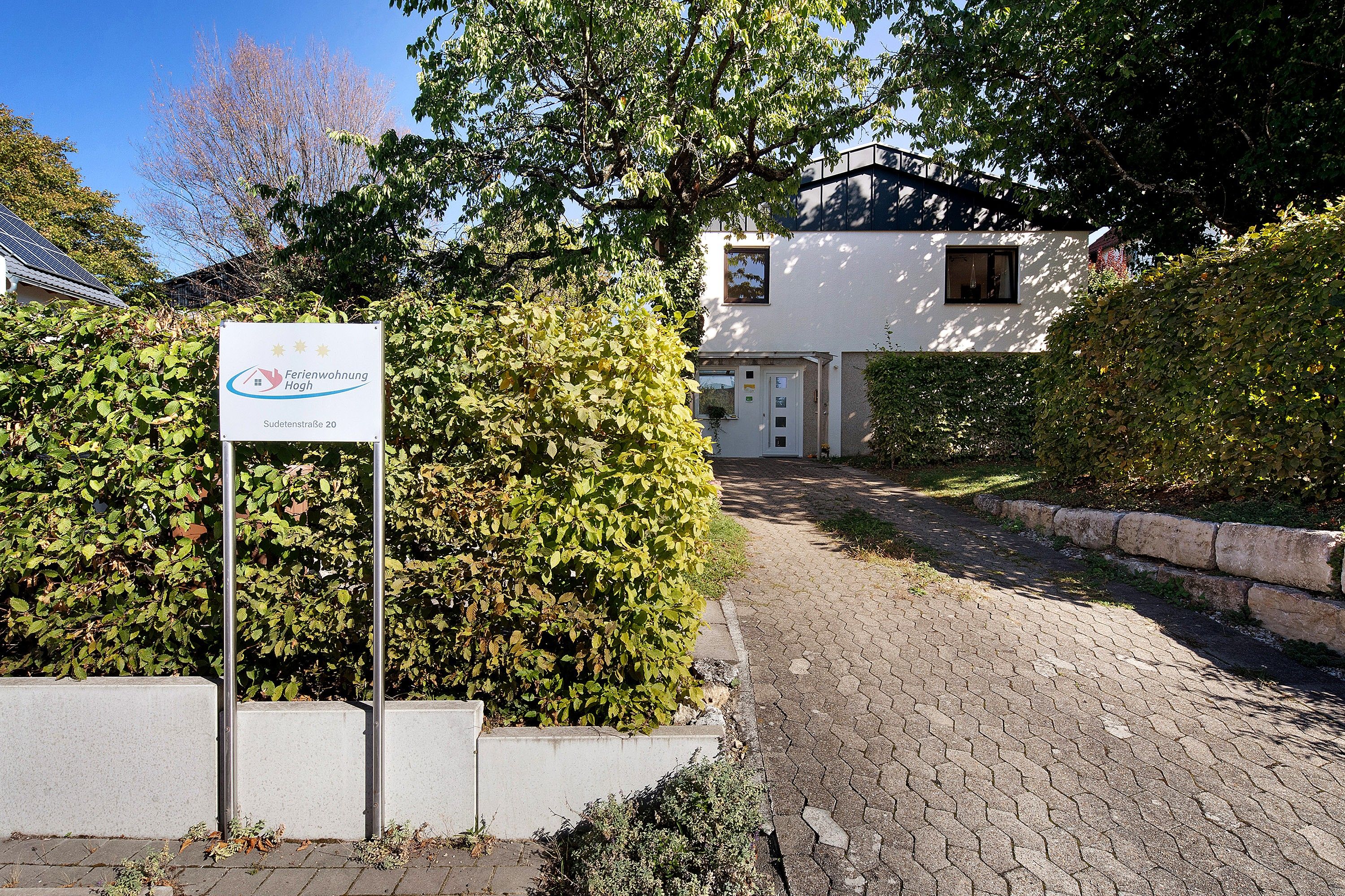 A residential property with a paved driveway leading to a white house with a dark roof.