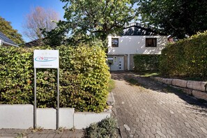 A residential property with a paved driveway leading to a white house with a dark roof.