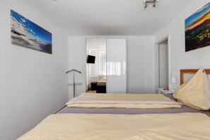 Une chambre d’hôtel avec un lit, une table de chevet, un miroir et un tableau au mur.