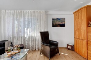 Un salon avec un fauteuil en cuir, une table basse en verre, un meuble en bois et un tableau accroché au mur.