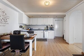 Une cuisine moderne avec des meubles blancs, une table à manger avec des chaises et un îlot de cuisine.