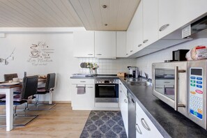 Una cocina moderna con armarios blancos, un horno Bosch, microondas integrado y una cafetera.