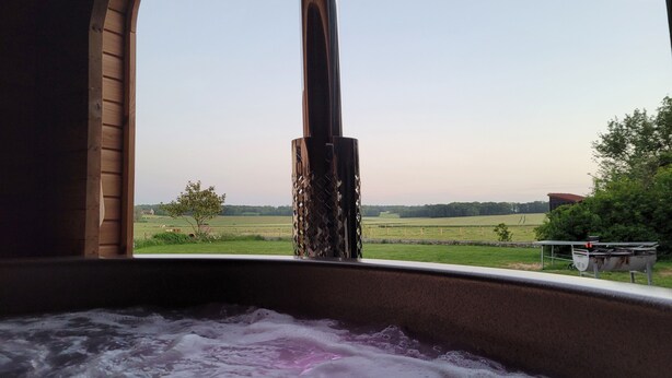 A hot tub with a view of a green field and a building in the distance. - Large capacity gîte in champagne.pets welcome! (Corrobert)