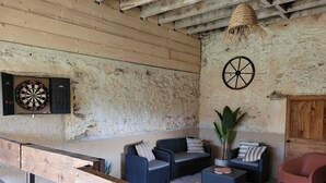 A rustic room with a dartboard, a large wheel, and seating arrangements. - Large capacity gîte in champagne.pets welcome! (Corrobert)