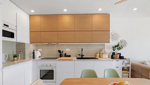 Eine moderne Küche mit weißen Schränken, einer Holz Arbeitsplatte und einem Essbereich mit Tisch und Stühlen.