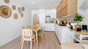 Eine moderne Küche mit weißen Schränken, einem Holztisch und einem Deckenventilator.