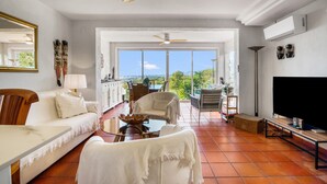 A spacious living area with a sofa, chairs, a TV, and a balcony with a view. - Holiday Home 'Oceanview House' with Sea View, Wi-Fi and Air Conditioning (Altea)