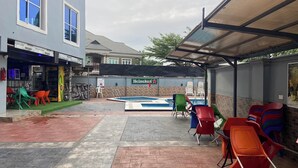 An outdoor patio with a swimming pool, colorful chairs, and a Heineken sign. - Haussefour Apartment (Abuja)