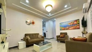 A modern living room with two sofas, a coffee table, and artwork on the walls. - Haussefour Apartment (Abuja)