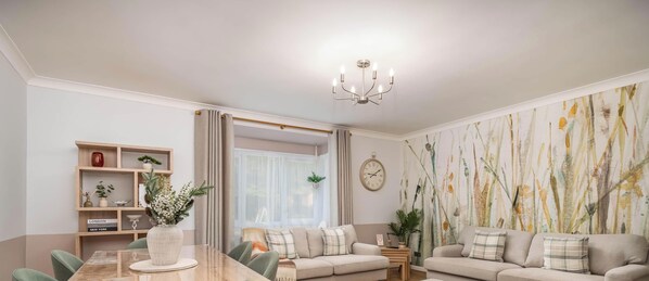 Ein modernes Wohnzimmer mit Esstisch, Sofas, einer Kandelaber und einem großen, abstrakten Gemälde an der Wand.