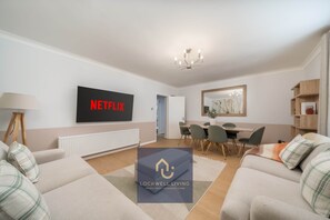 A modern living room with a flat-screen TV, a dining area, and a cozy seating arrangement.