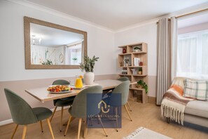 Ein modernes Wohnzimmer mit Essbereich, einem großen Spiegel und einem Bücherregal.