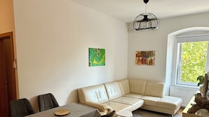 A modern living room with a sofa, dining table, chairs, and artwork on the walls.