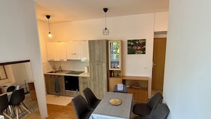 A compact kitchen with white cabinets, a built-in oven, and a dining area with a table and chairs.