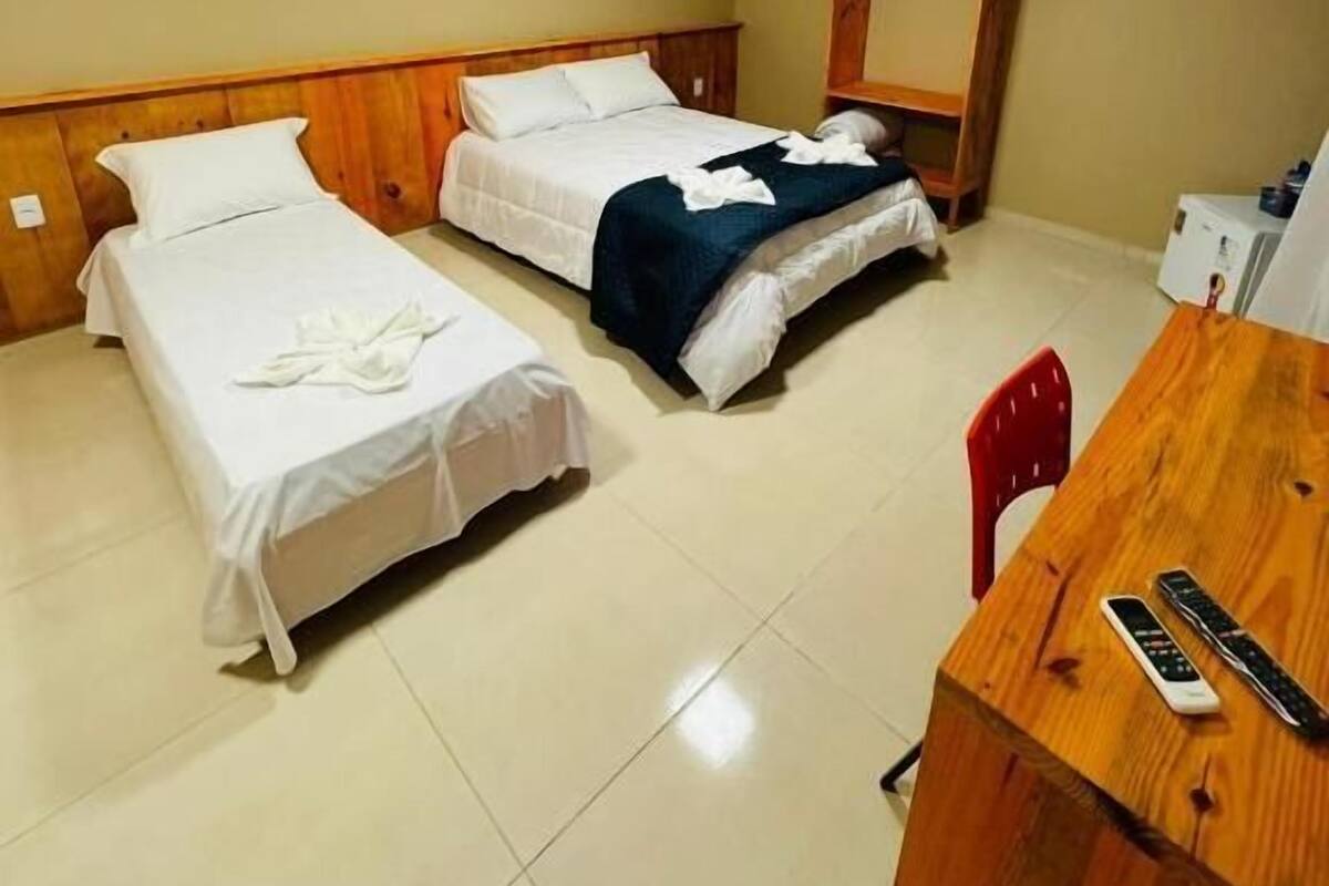 A hotel room with two single beds, a wooden desk, and a red chair.