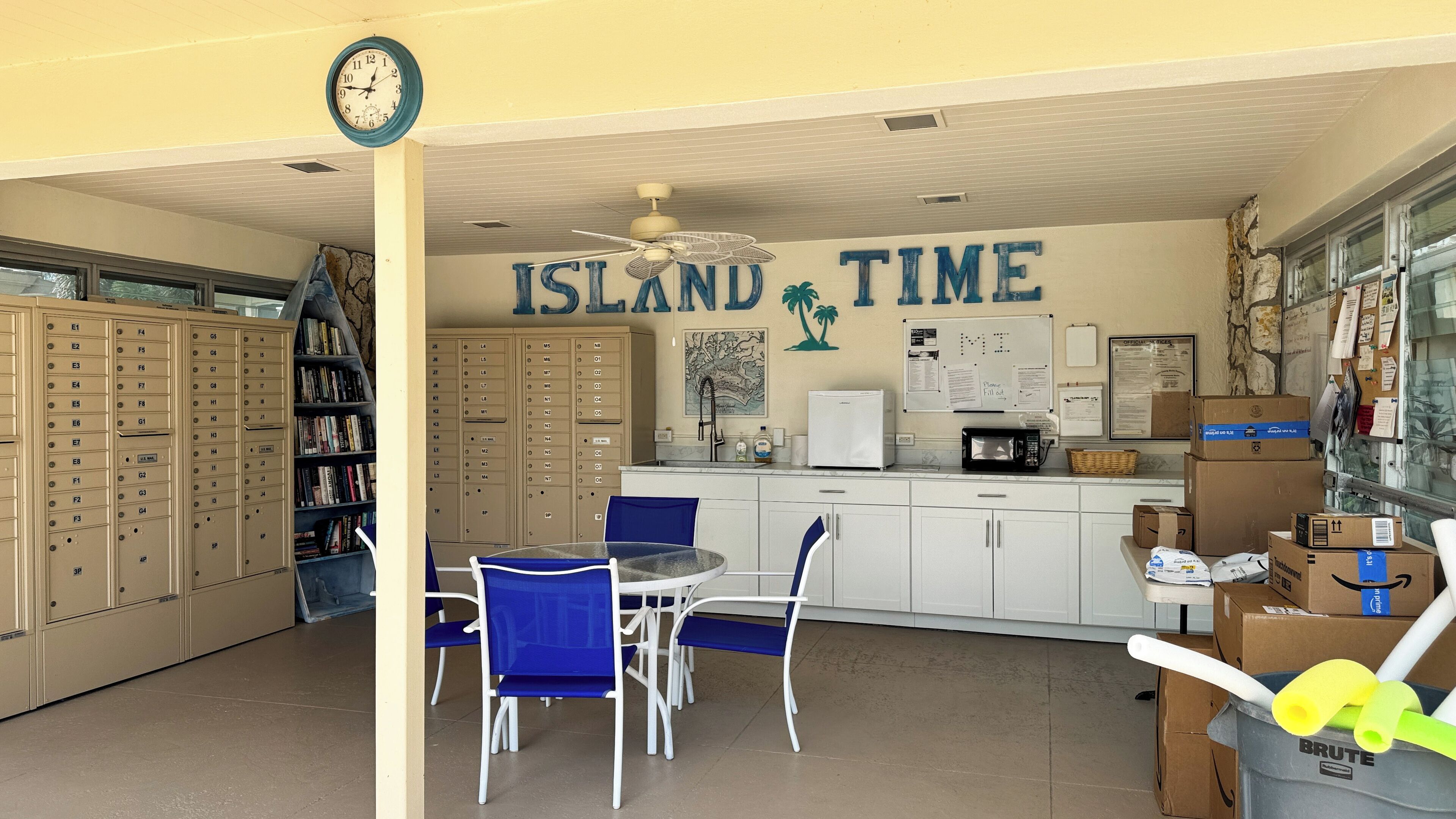 Een bibliotheek met boekenplanken, een klok, een tafel met stoelen en een muur waarop 'ISLAND TIME' staat.