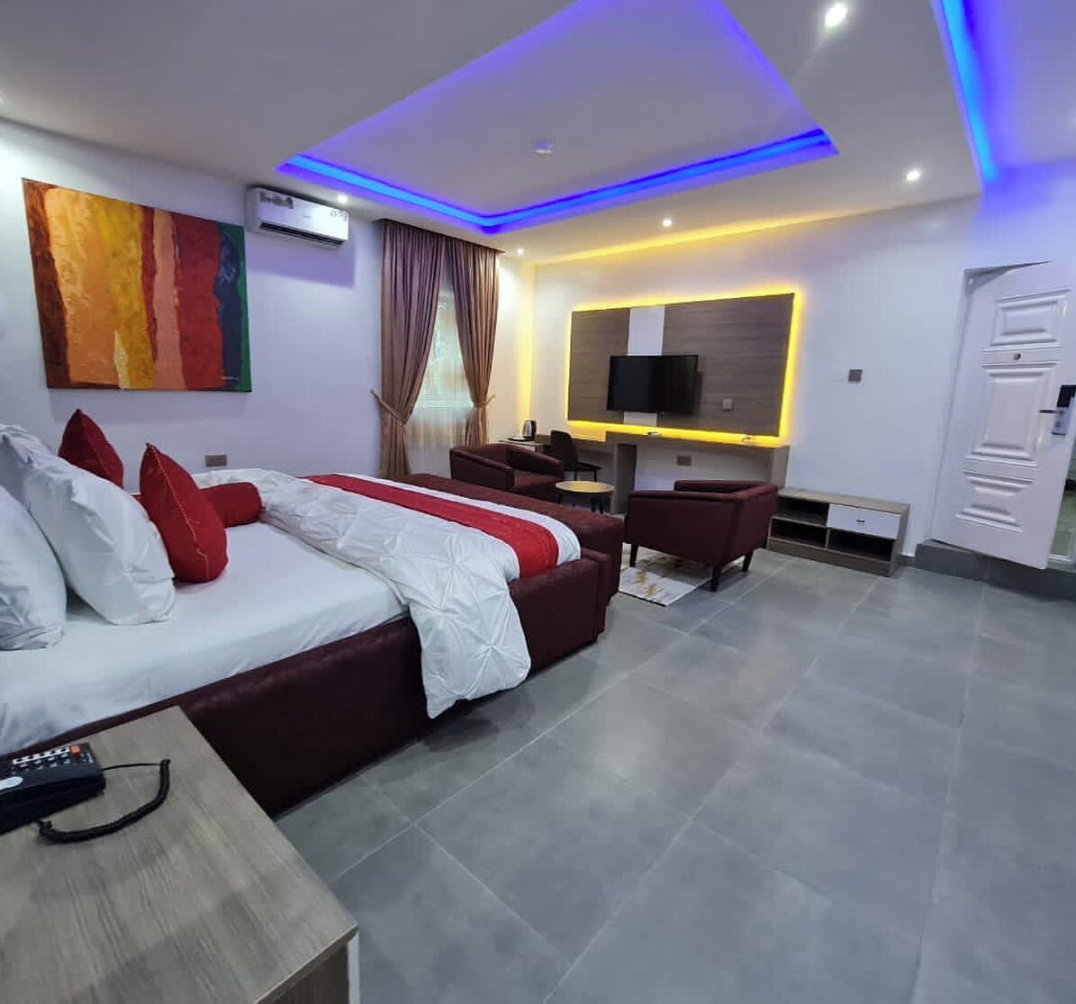 Quarto de hotel moderno com uma cama grande, uma escrivaninha, uma televisão e um guarda-roupa.