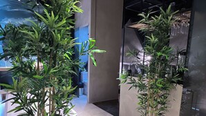 A modern interior with potted bamboo plants, a tiled floor, and a visible air conditioning unit. - Hotel Lleras Park II (Medellín)