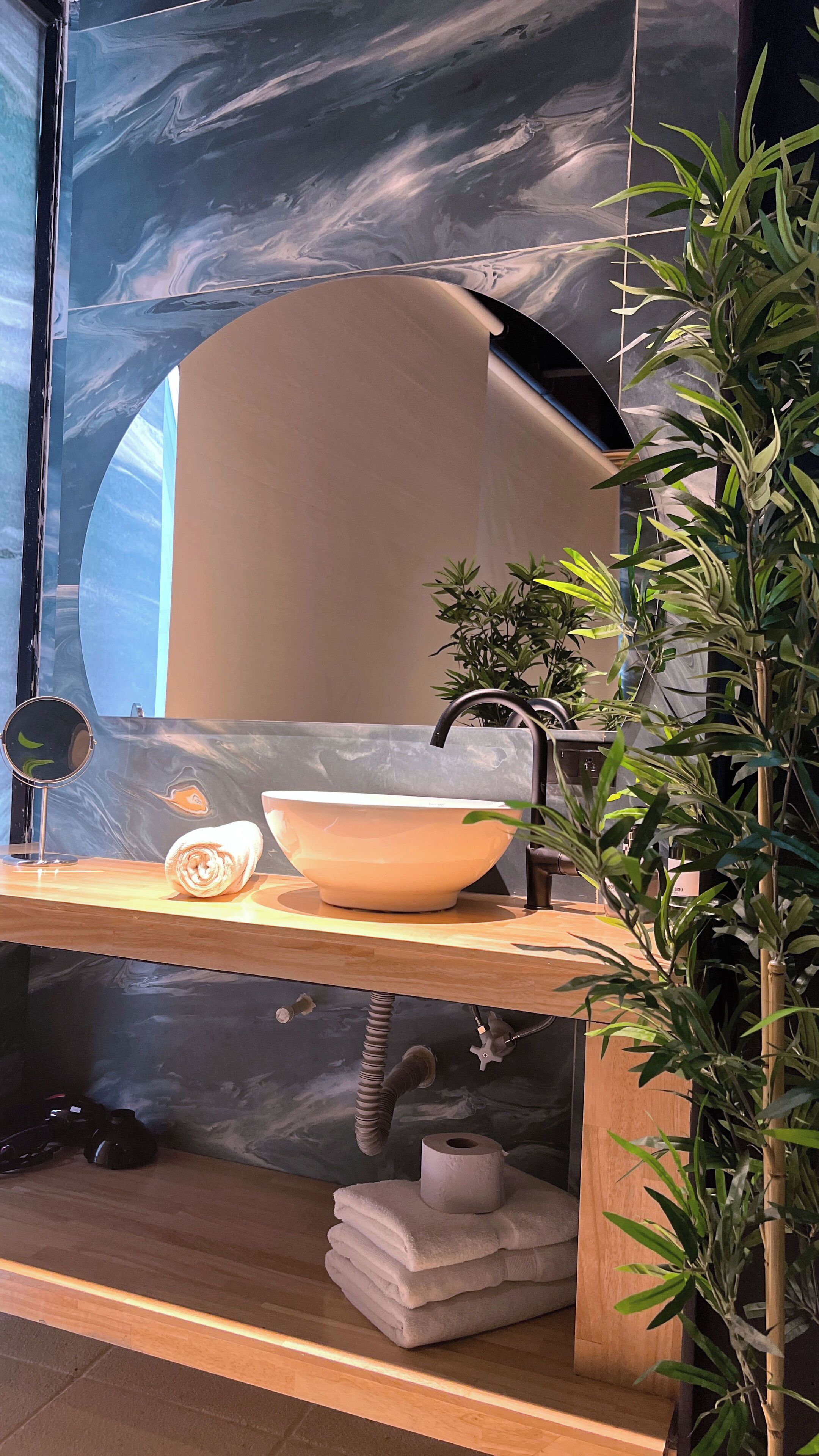 A bathroom with a marble backsplash, a sink with a faucet, a mirror, and a towel rack.