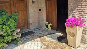 Une cour intérieure agrémentée d’arches en briques, de portes en bois, d’un sol en pierre et d’un jardinier planté de fleurs.