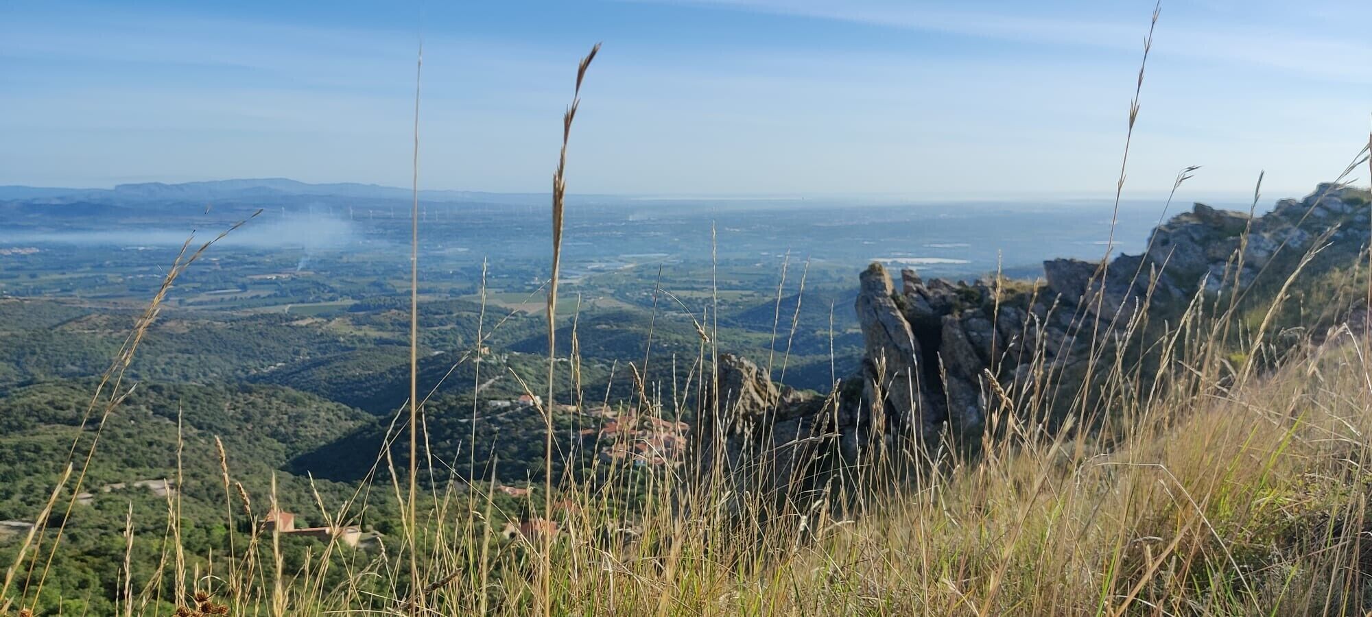 Un paysage montagneux offrant une vue sur une vallée et des montagnes lointaines.