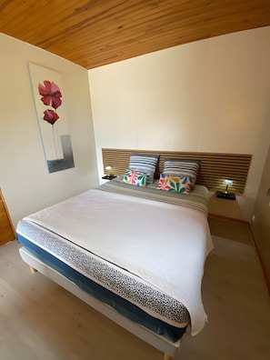 Une chambre à coucher comprenant un lit, une tête de lit, une table de chevet, une lampe et une œuvre d’art murale.