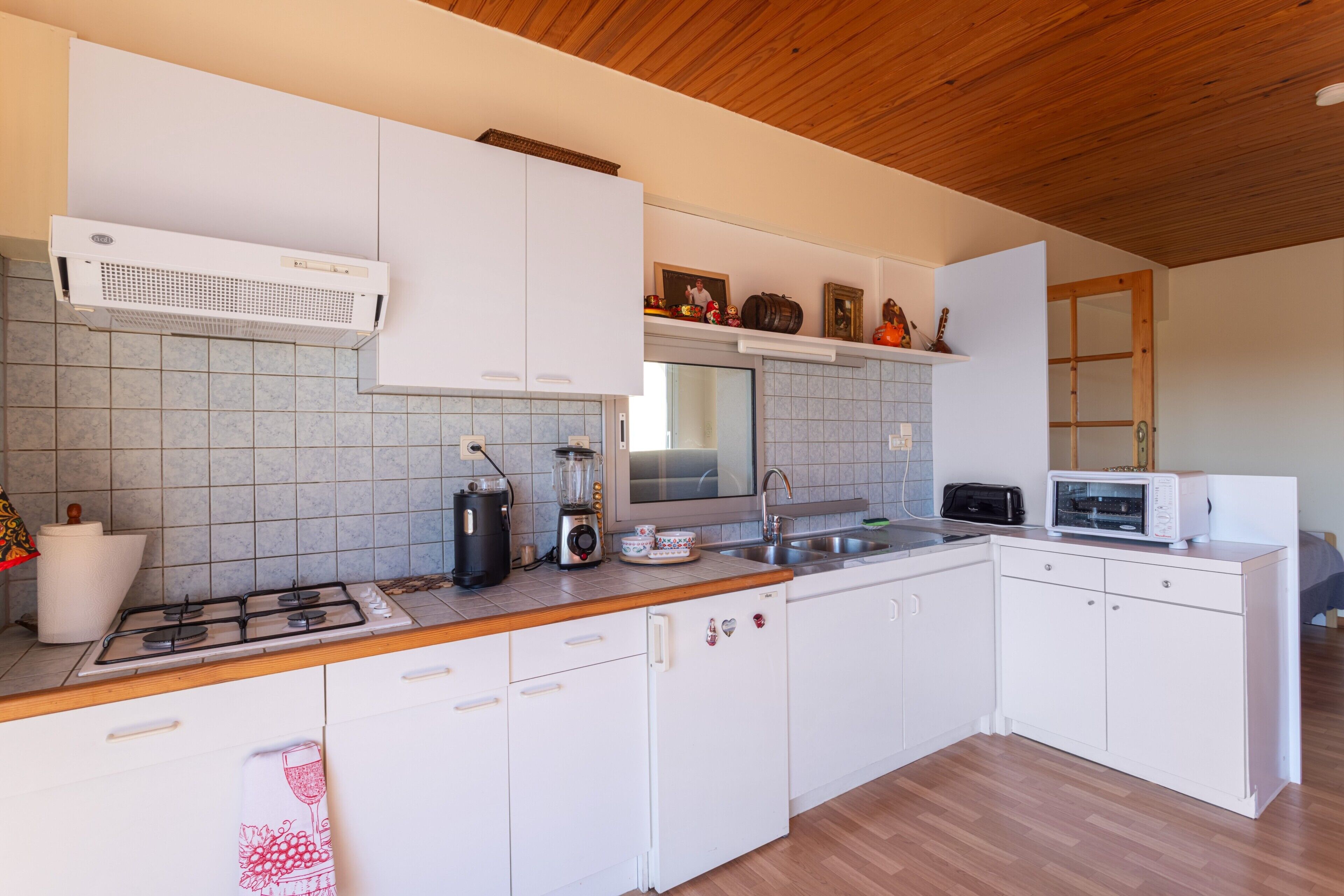 Una cocina moderna con armarios blancos, estufa a gas, microondas y licuadora.