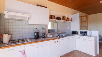 Una cocina moderna con armarios blancos, estufa a gas, microondas y licuadora.