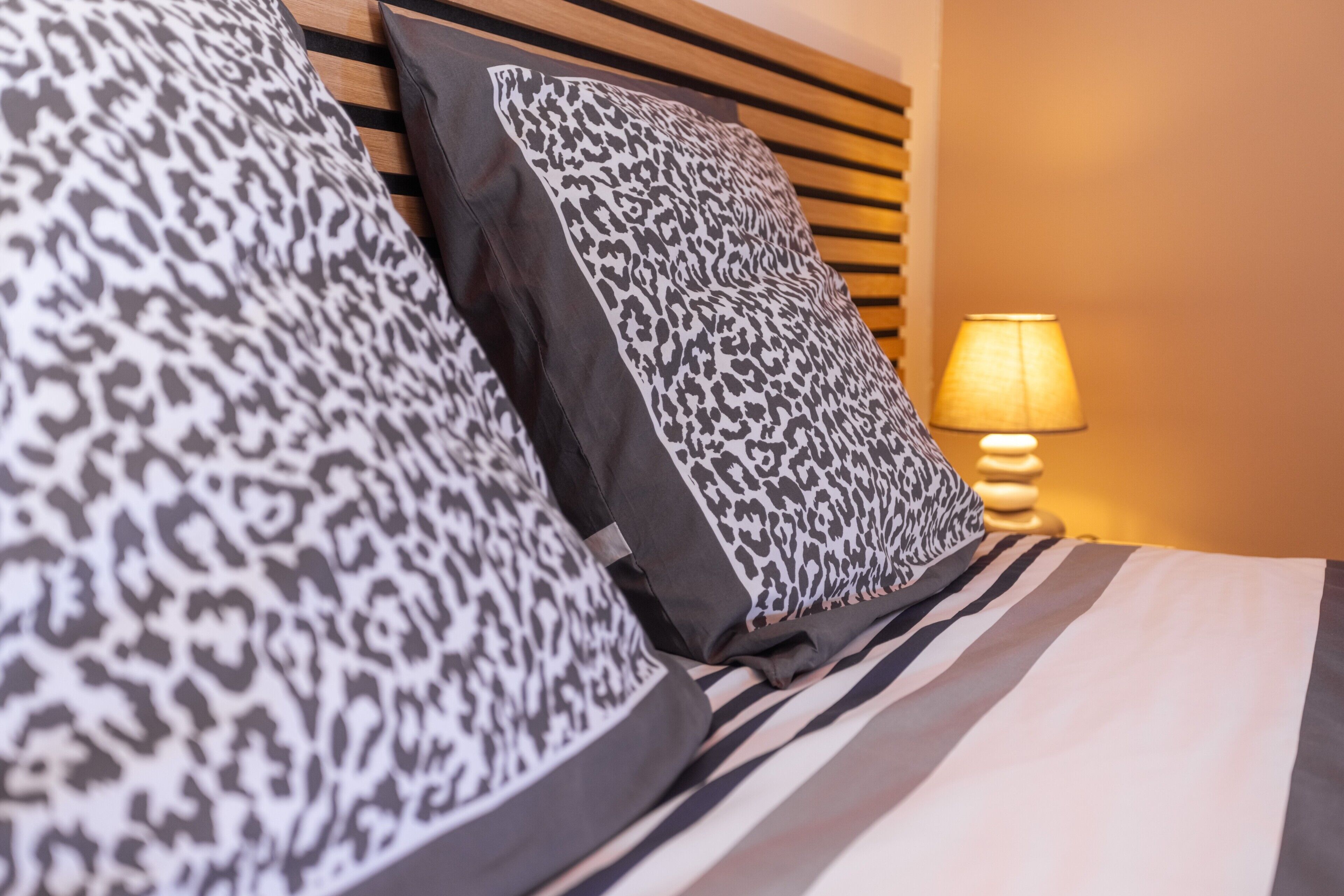 Ein Bett mit gestreifter Bettwäsche und zwei Kissen mit Leopardenmuster.