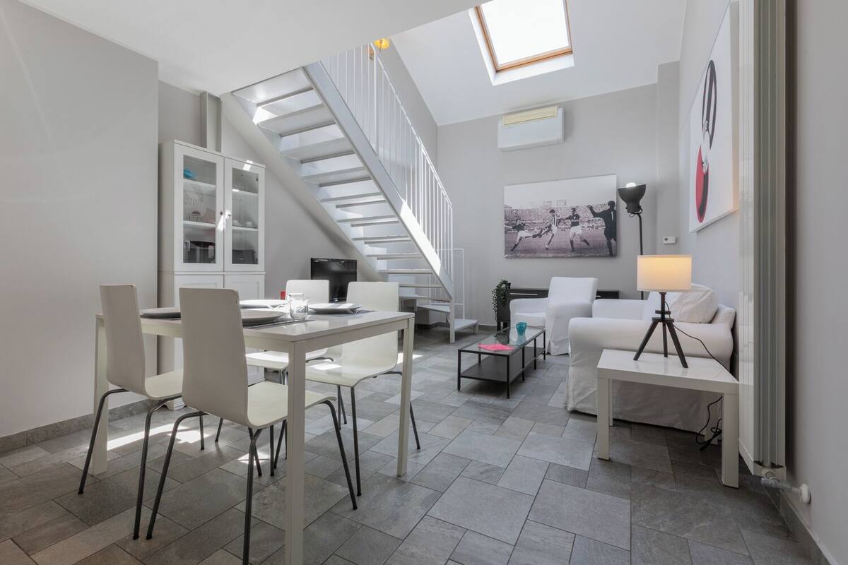 Un appartamento moderno con zona pranzo, soggiorno e una scala che conduce a un piano superiore.