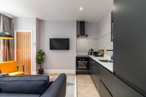A modern kitchen with a built-in oven, a black range hood, and a stainless steel sink. - Chelmsford Loft 8 in Newcastle Upon Tyne (Newcastle-upon-Tyne)
