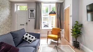 A modern living room with a sofa, a yellow armchair, a floor lamp, and a potted plant. - Chelmsford Loft 8 in Newcastle Upon Tyne (Newcastle-upon-Tyne)