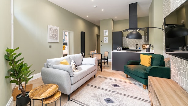 Uma sala de estar moderna com dois sofás, um espaço de refeições e uma cozinha.