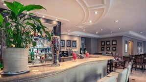 A bar area with a curved counter, seating, and a large potted plant. - Pinheiros Luxury Flat in a 4-star hotel (São Paulo)