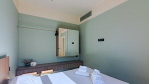 Ein Hotelzimmer mit Bett, Nachttisch mit Lampe, Spiegel und Wandheizung.