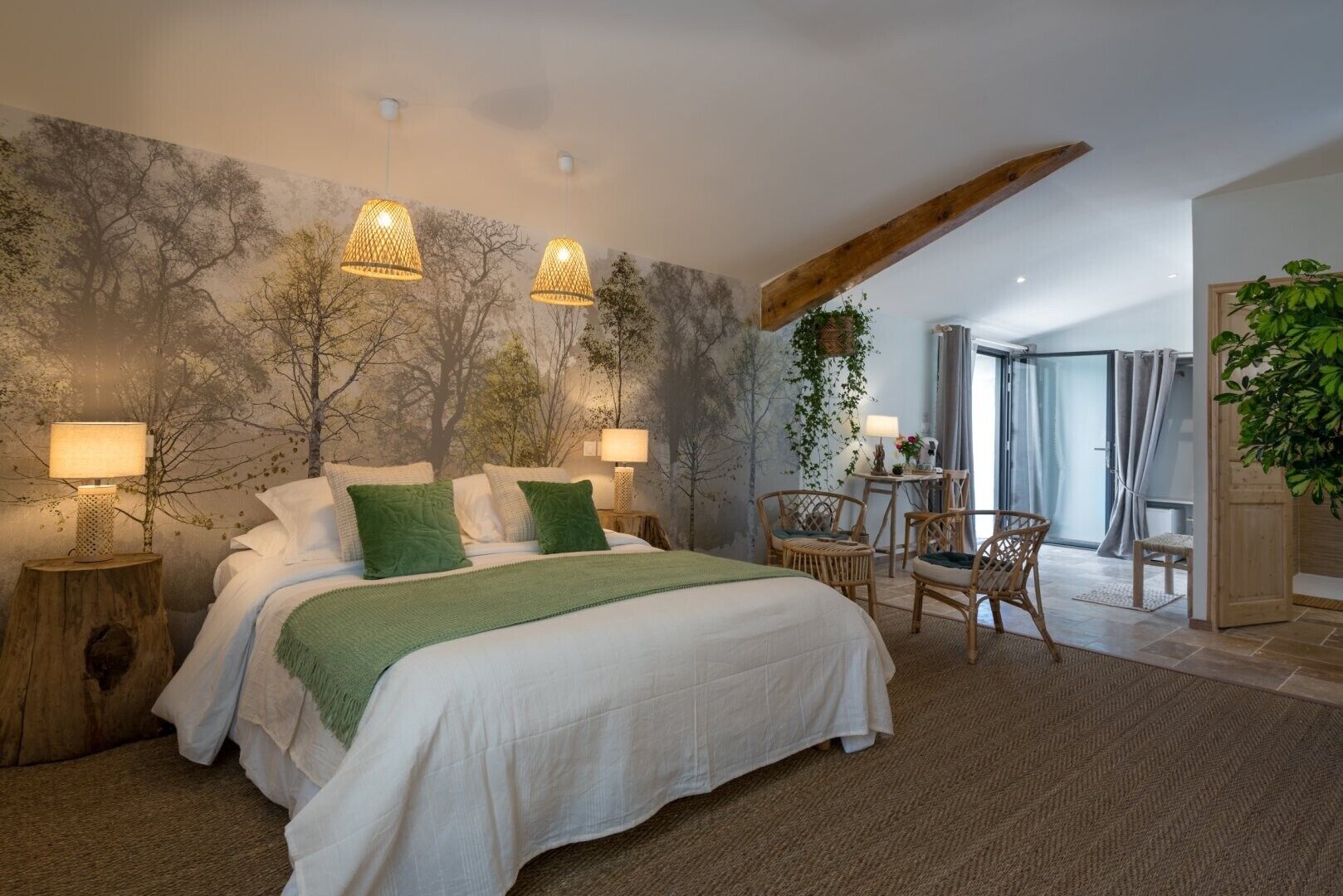 Quarto com cama, duas luminárias de cabeceira, uma cadeira, uma mesinha e vista para o exterior.