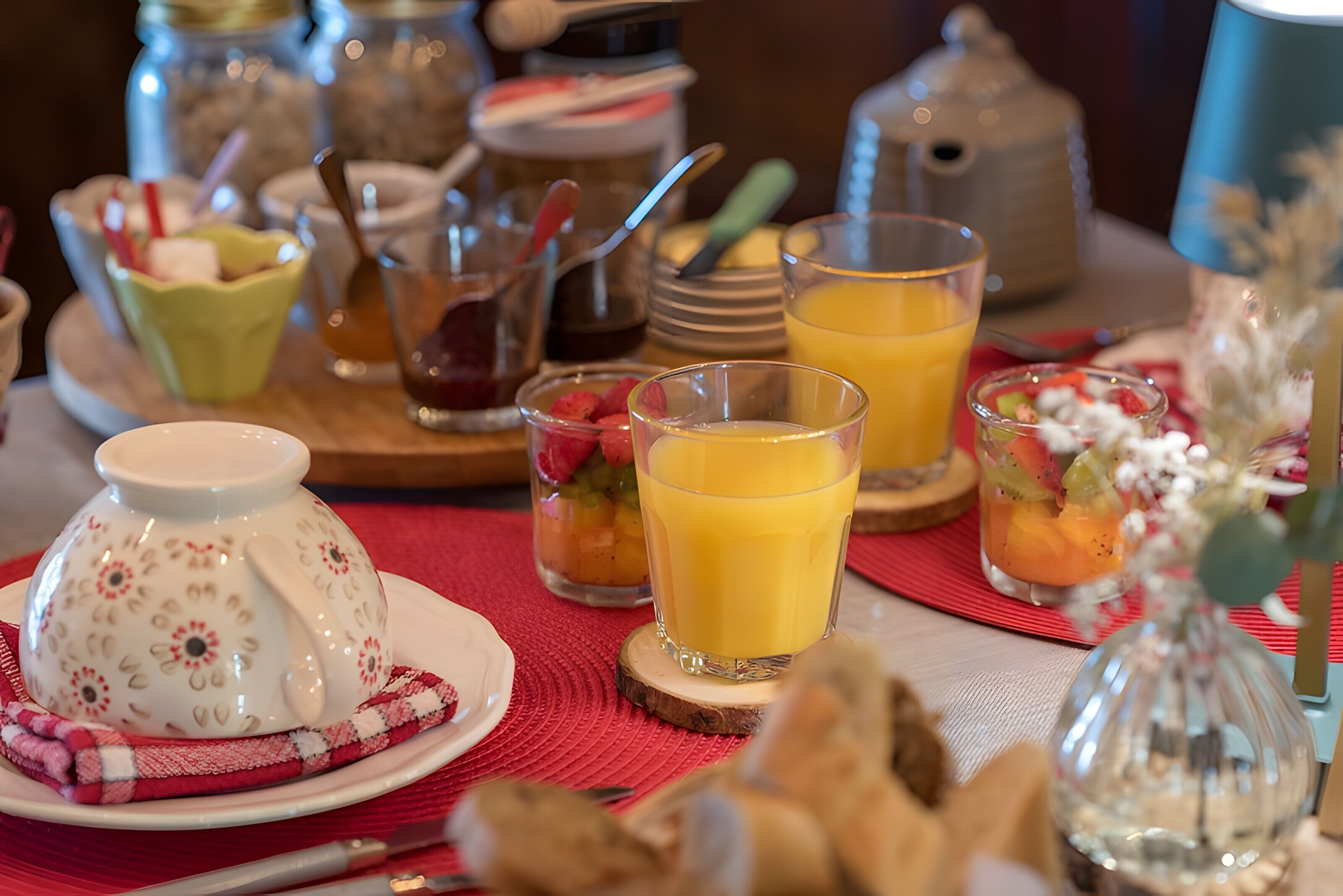 A breakfast setting with a teapot, cups, and a variety of fruits and pastries.