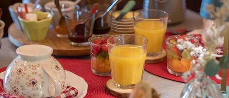 A breakfast setting with a teapot, cups, and a variety of fruits and pastries.