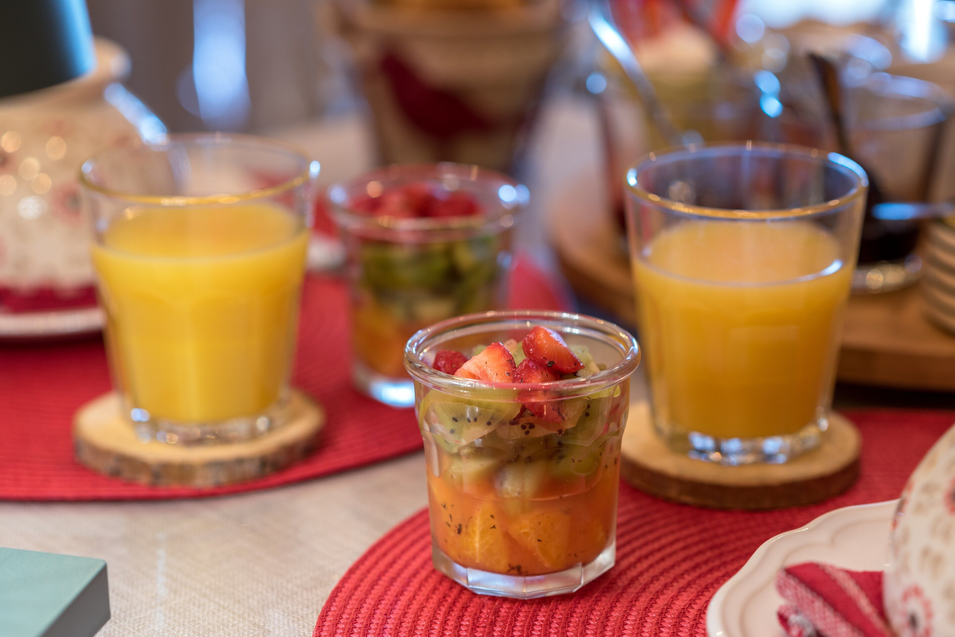 A table with various food items and drinks, including a fruit salad and glasses of orange juice.