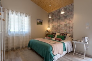 Une chambre avec un plafond en bois, un lit avec une literie verte et rose, une table de chevet avec une bouilloire, et un mur recouvert de carreaux décoratifs.