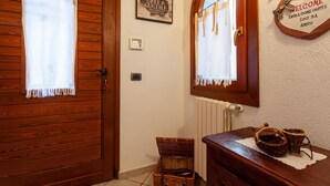 A wooden door with a window, a wall-mounted mirror, a welcome sign, and a wicker basket on a table. - A Stone's Throw from Aosta (Pollein)