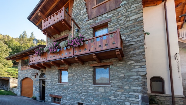 A stone building with wooden balconies, a garage, and a small window. - A Stone's Throw from Aosta (Pollein)