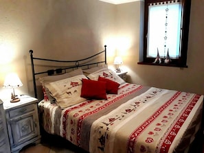 Un lit recouvert d’une couvre-lit à motifs, deux lampes de chevet, une table de chevet avec une lampe et une fenêtre décorée d’étoiles.
