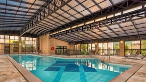 An indoor swimming pool with a glass ceiling, stone flooring, and lounge chairs around the pool. - Maria Flat in Pinheiros equipped in a 4-star hotel - 4 (São Paulo)